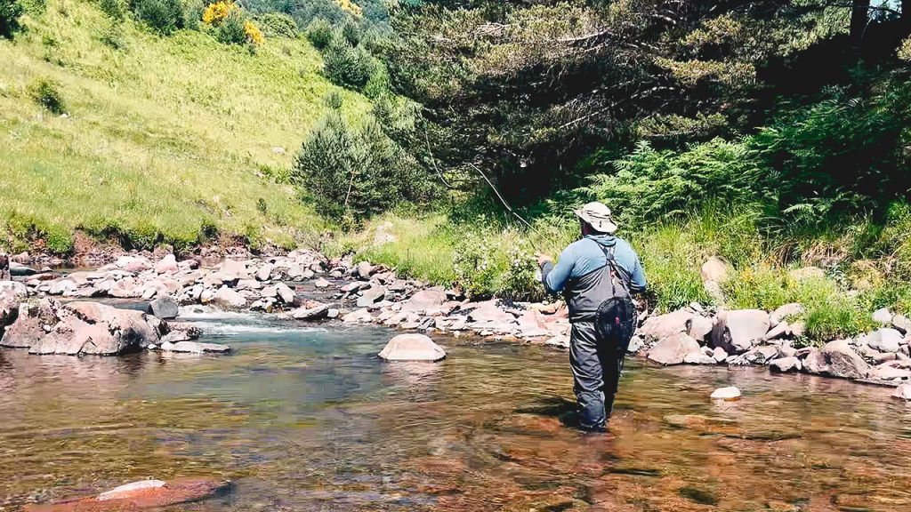 Angler making a blind cast on a clear mountain river, focused and calm, northern Spain
